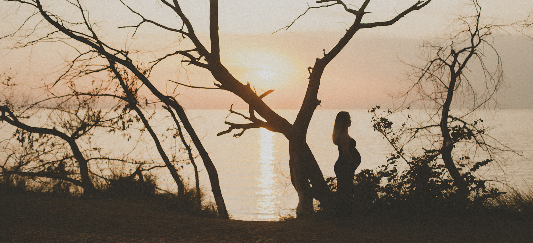 Photo of a pregnant woman at the sunset.